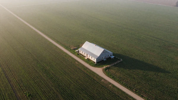 Isolated farmhouse surrounded by green fields, representing rural dating challenges