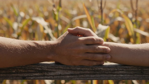 Close-up of couple holding hands on a farm fence, how to date a farmer guide