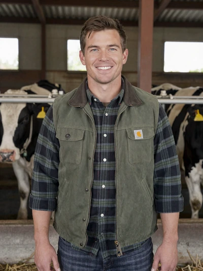 Caleb, 36, Ohio dairy farmer smiling in front of milking parlor in Wayne County