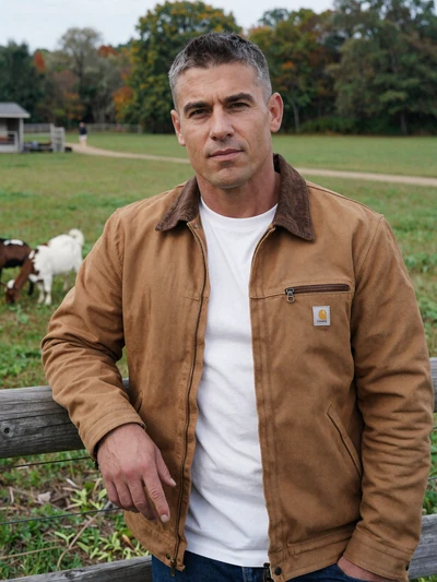 Eli, a 44-year-old Jewish-American farmer leaning on a fence with goats in his Ohio pasture