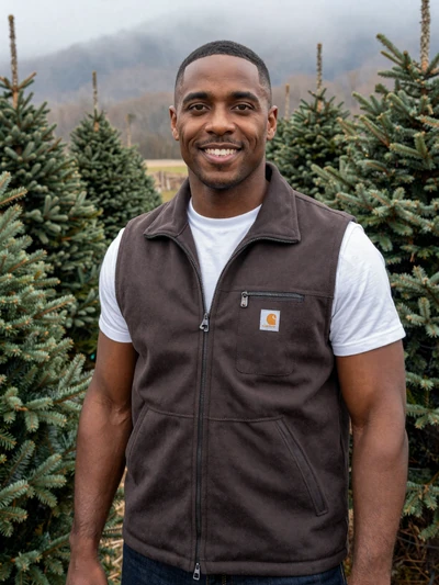 Marcus, 37, North Carolina Christmas tree farmer smiling among Fraser firs in Avery County